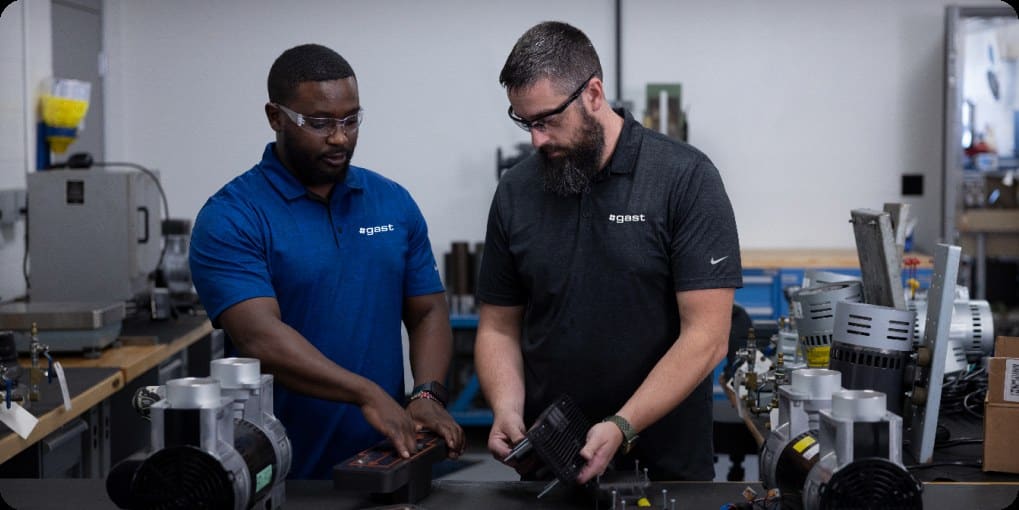 Two engineers reviewing pneumatic components at a workbench