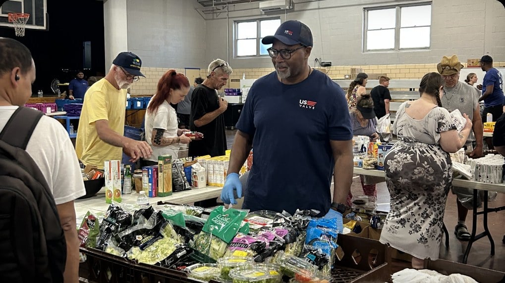 Un volontario di US Valve che presta aiuto presso un banco di distribuzione alimentare della comunità